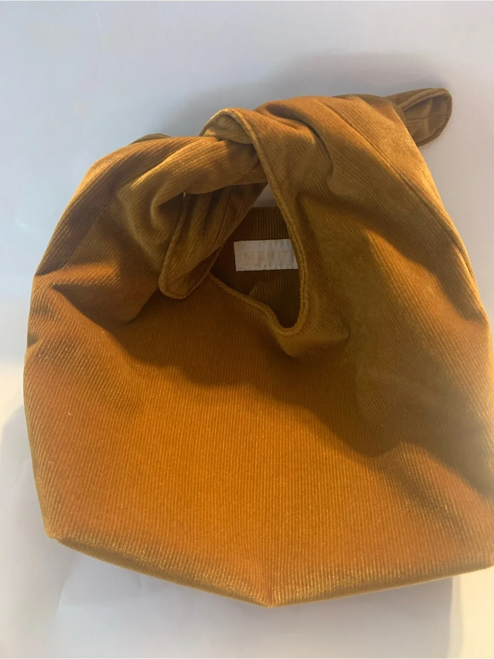 Merit Beauty Signature Bag in a golden brown or camel corduroy material
